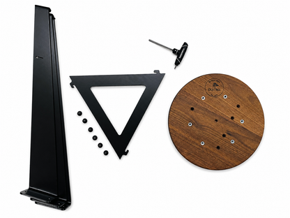 A set of black metal mounting hardware and a round wooden board with pre-drilled holes, photographed on a clean white background. The set includes a tall angled bracket, a triangular alignment tool, a small hex key, screws, and a circular wood panel.