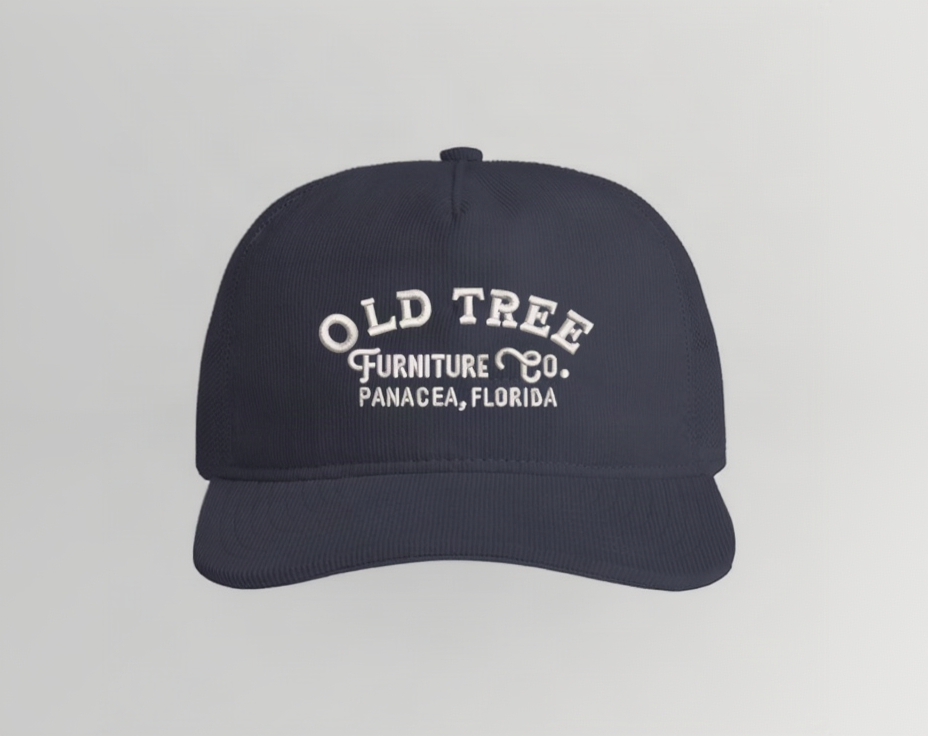 A dark navy blue baseball cap with white embroidered text reading 'OLD TREE FURNITURE Co. PANACEA, FLORIDA' on the front, shown against a plain white background.